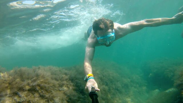 A selfie shot underwater by a Caucasian man sporting a physique floats beautifully underwater. The concept of free diving and recreation on the sea coast or on the ocean