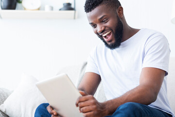 Emotional african fan watching sports online on digital tablet