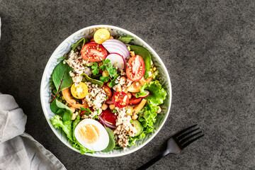 Fresh vegetable salad in a plate on a black background. Top view