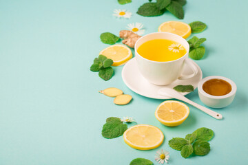 Herbal tea of chamomile flower with mint, ginger, lemon, honey on paper blue background.