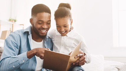 Weekend together. Loving father reading book to his daughter