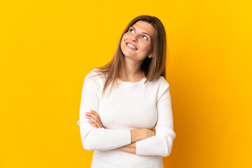 Fototapeta premium Young Slovak woman isolated on yellow background looking up while smiling