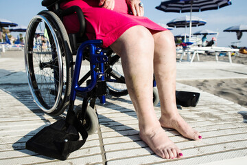 Obraz na płótnie Canvas legs detail od disabled woman sitting on a wheelchair at the beach
