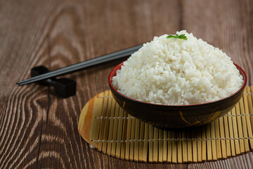 White rice is placed in a cup on the wooden floor.