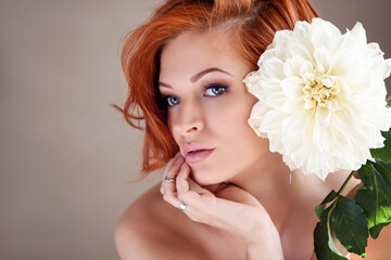 Obraz na płótnie Canvas Portrait of young beautiful redhaired woman with white flower. Beauty portrait