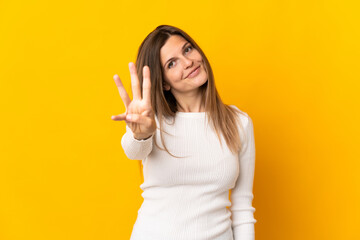 Young Slovak woman isolated on yellow background happy and counting three with fingers