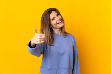 Young Slovak woman isolated on yellow background with thumbs up because something good has happened