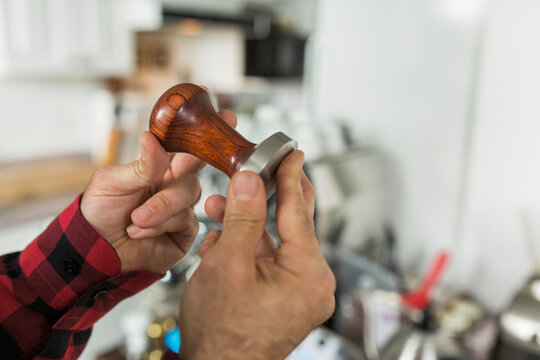 A man holding a coffee tamper