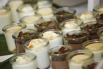Viele Gläser mit Dessert wie Panna Cotta, Mousse au Chocolat und Dekoration.