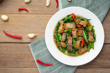 Stir fried kale, spicy crispy pork on wooden table Thai food concept.