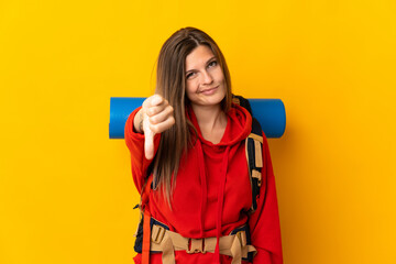 Slovak mountaineer woman with a big backpack isolated on yellow background showing thumb down with negative expression