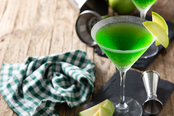 Green appletini cocktail in glass on wooden table. Copy space	