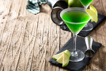 Green appletini cocktail in glass on wooden table. Copy space	