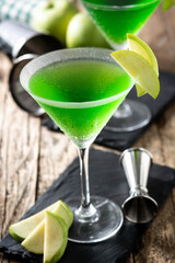 Green appletini cocktail in glass on wooden table 	