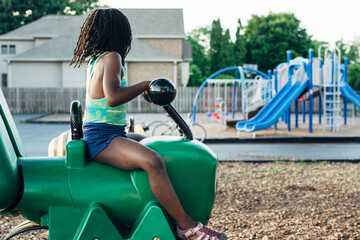 Young black girl riding on a cricket at a playground