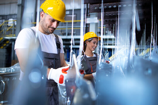 Experienced workers checking quality of metal parts at production line in factory. Metal industry.