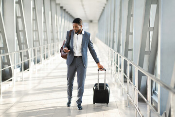 Entrepreneur Using Smartphone Walking In Airport With Suitcase Indoor