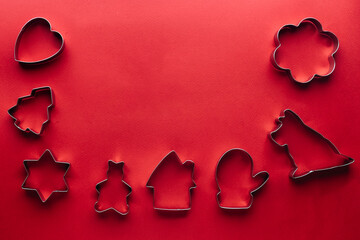 Christmas cookie cutters on red background with copy space. Heart, tree, star, bear, house, mitten, dog, flower forms. Top view. Flat lay. Trendy colorful photo. Minimal style. Christmas concept.
