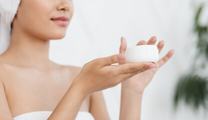 Jar with cream in young asian woman hands
