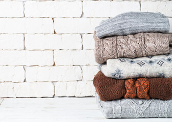 Stack of cozy woolen clothes on white.
