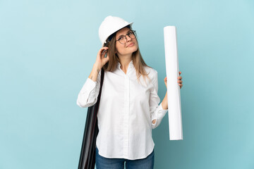 Slovak architect girl holding blueprints isolated on blue background having doubts