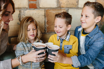 A mother and her sons drinking cups of hot chocolate / cocoa
