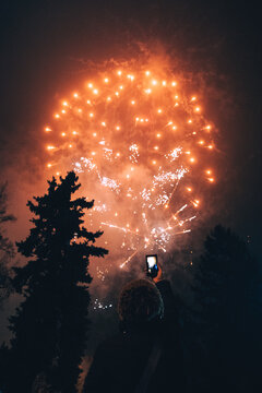 Woman taking photos of fireworks using smartphone