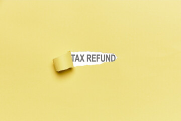 Yellow broken paper background with the word TAX REFUND. Finance