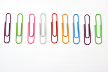 Set of colored stationery paper clips laid out in a row on a white background.