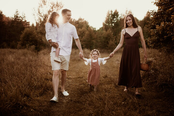 Fototapeta premium Beautiful happy young family with two children in a field in summer, daughter with Down syndrome in a Caucasian family, lifestyle and brown toning. Candide childhood and motherhood