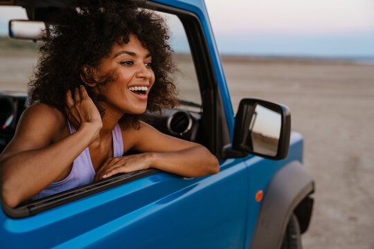 Image of cheerful african american woman smiling while travelling in car