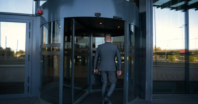 Businessman in a fromal suit in a business center enter the building with briefcase.