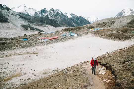 Female trekker climbing a track with Gorak Shep village in the background, Everest Region, Nepal.