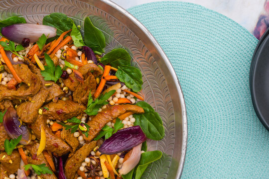 moroccan beef salad with carrot and cous cous on an aqua blue pl