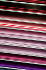 Stacks of colored paper in various shades of pink, red and purple