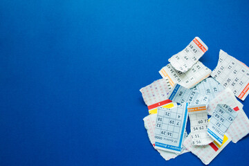 Torn lottery tickets with numbers on a dark blue background.  On the pieces - fragments of the...