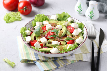 Healthy salad with avocado, tomatoes, feta and red onion on grey background, healthy eating day