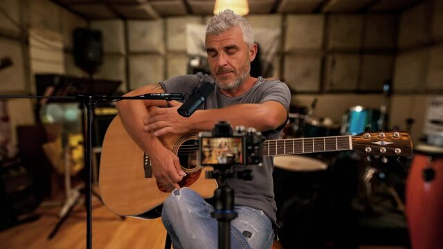 vlog tutorial man teaching to play guitar online recording himself,guitarist youtuber record a video in his studio recording room for his followers