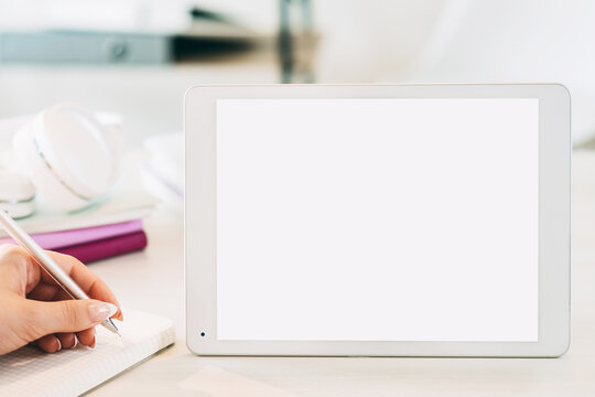 Video conference. Virtual office. Tablet with copy space blank white screen female hand writing notes at home workplace. Online corporate meeting. Coronavirus quarantine. Social distancing.
