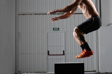Fit man jumping on gym box for workout