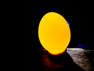 The light is on the back of the egg and the egg is bright yellow.