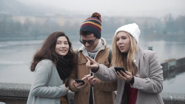 Three friends looking at mobile map and standing in Prague city. Travel, friendship, lifestyle, holiday concept. Filmed on RED camera, 10 bit clolor