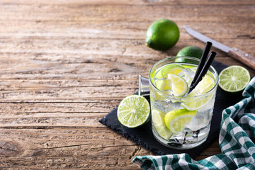 Caipiroska cocktail with lime on wooden table. Copy space	