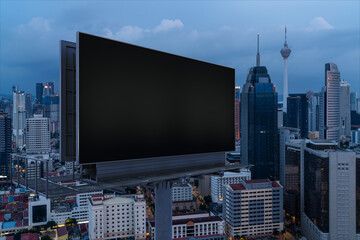 Blank black road billboard with KL cityscape background at night time. Street advertising poster, mock up, 3D rendering. Side view. The concept of marketing communication to promote or sell idea.