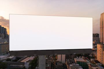 Blank white road billboard with Bangkok cityscape background at sunset. Street advertising poster, mock up, 3D rendering. Front view. The concept of marketing communication to promote or sell idea.