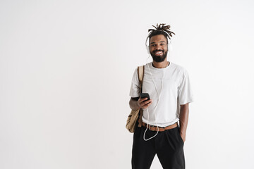 Photo of joyful african american guy using mobile phone and headphones