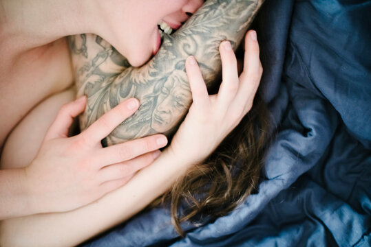 Girl bites the tattooed arms of her boyfriend