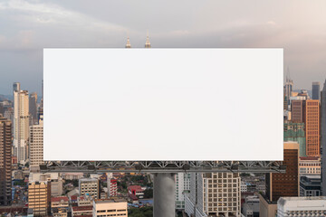 Blank white road billboard with Kuala Lumpur cityscape background at sunset. Street advertising poster, mock up, 3D rendering. Front view.