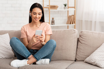 Obraz premium Portrait of lady wearing headphones enjoying music with phone
