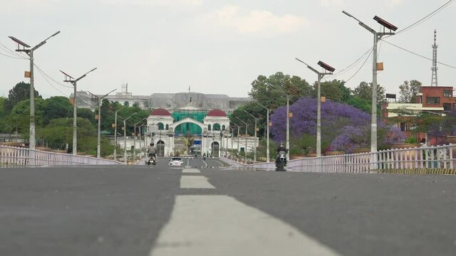Motor scooters driving along asphalt road leading to main gate of Singha Durbar